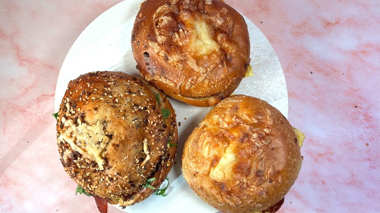 Overhead shot of three Panera Asiago Bagel Stacks on white platform, pink marble background