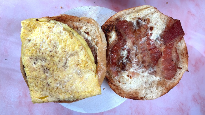 Overhead shot of open Panera Farmhouse Duo Asiago Bagel Stack on white platform, pink marble background