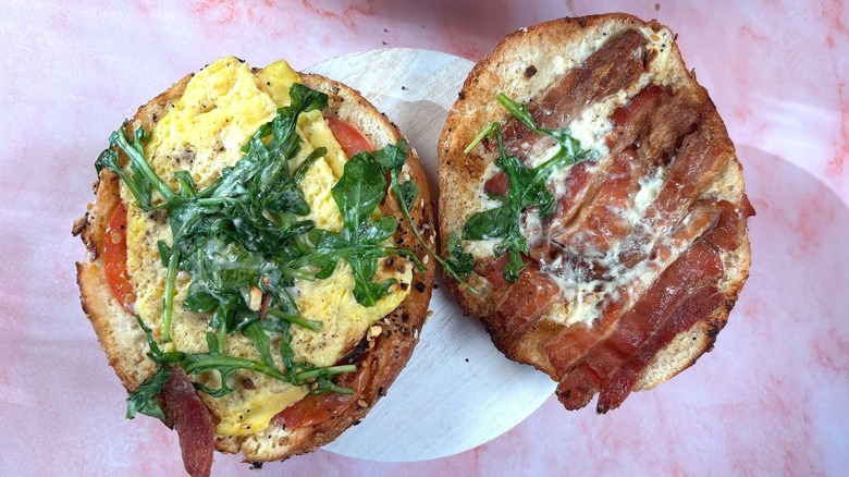 Top-down of open Panera Wake-Up BLT Asiago Everything Bagel Stack on white platform, pink background