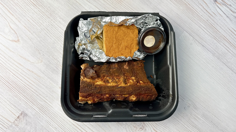 Mission BBQ ribs and cornbread in a black plastic container