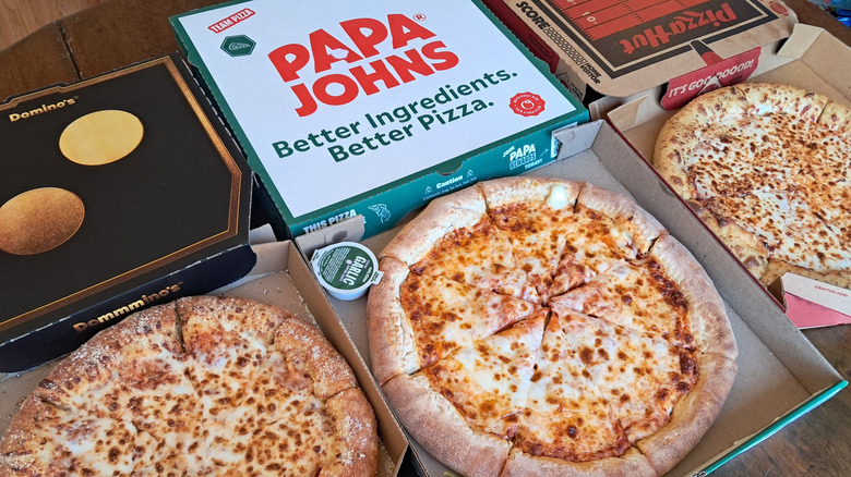 Three pizzas in boxes on table