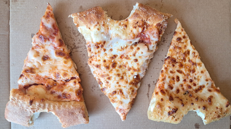 Three slices of pizza with bite taken out of the crust