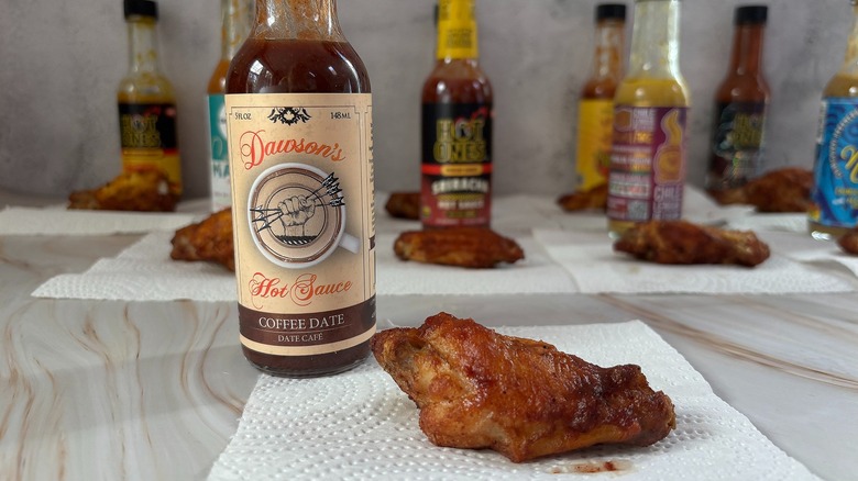 Bottle of Dawson's Coffee Date hot sauce on table next to chicken wing