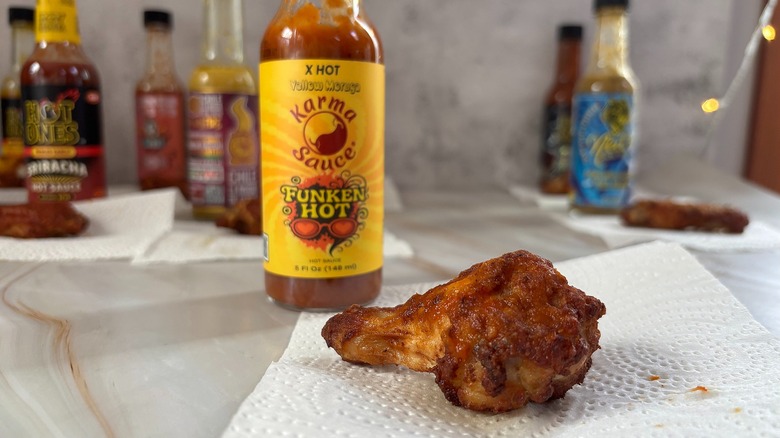 Bottle of Funken Hot hot sauce on table next to chicken wing