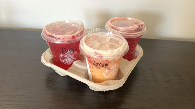 Three Starbucks Mango Strawberry Refreshers in drink carrier.