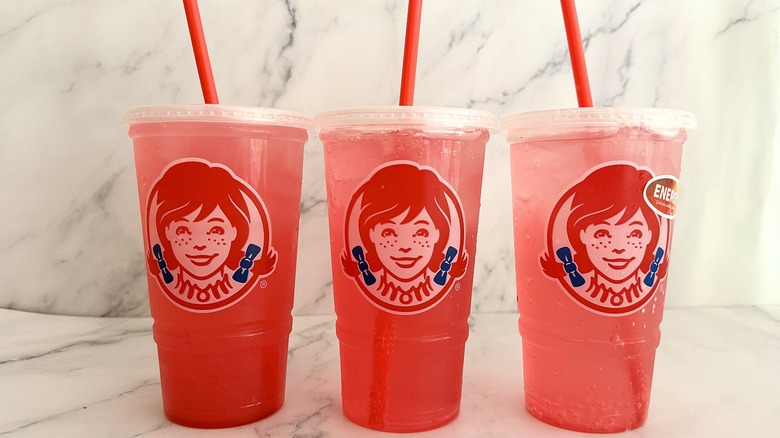 Three Wendy's watermelon drinks in line on marble surface