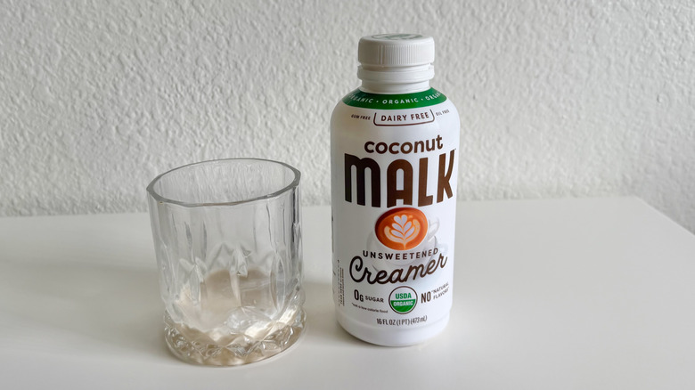Malk unsweetened creamer container next to glass