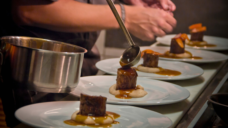 A series of identical plates being prepped in a fine dining kitchen