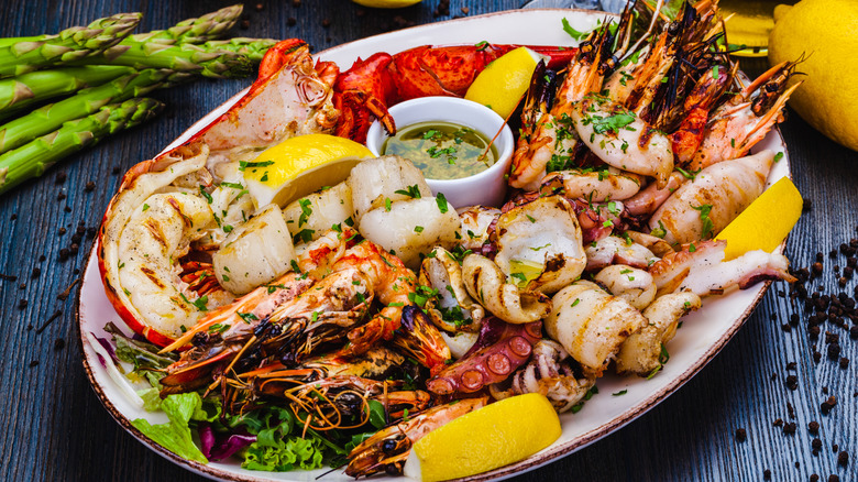 Giant seafood platter with various options like lobster, scallops, prawns, and octopus with a dip and lemon slices