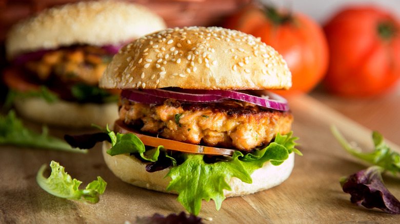Salmon burger on sesame bun with onions and lettuce