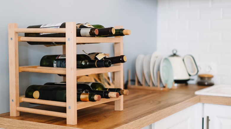 Home wine rack with opened and unopened wines on kitchen counter