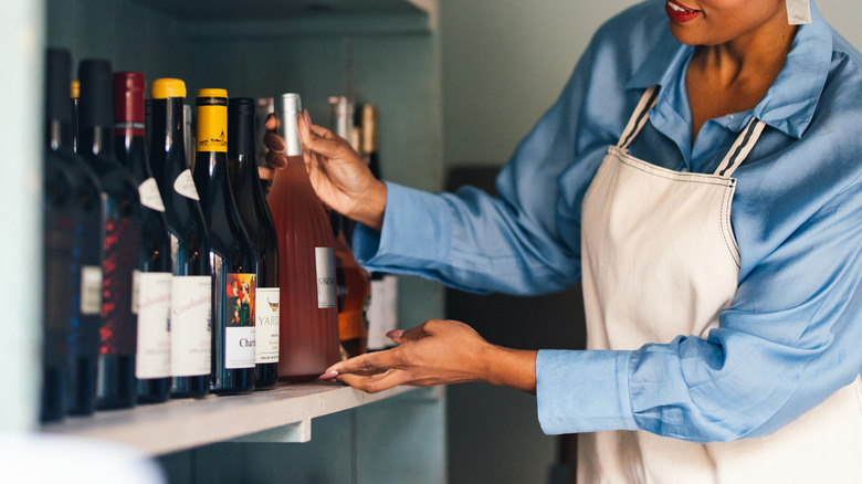 Woman selecting bottle from home wine rack