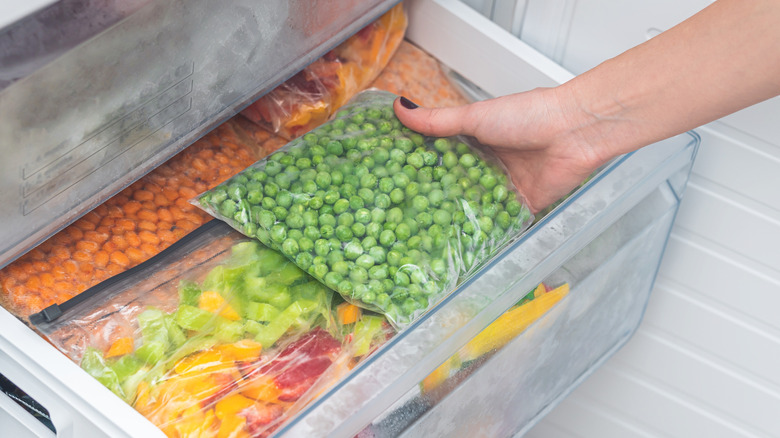 hands removing vegetables from the freezer
