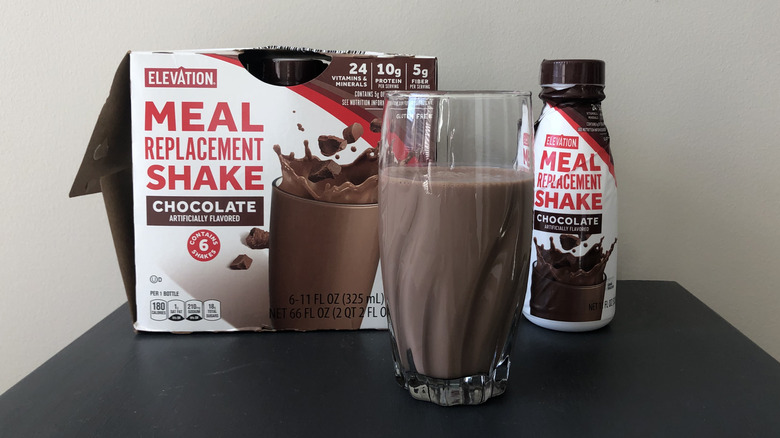 Protein shake in a tall glass in front of the packaging