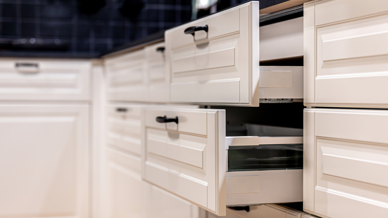 Two half-open white kitchen drawers with black hardware