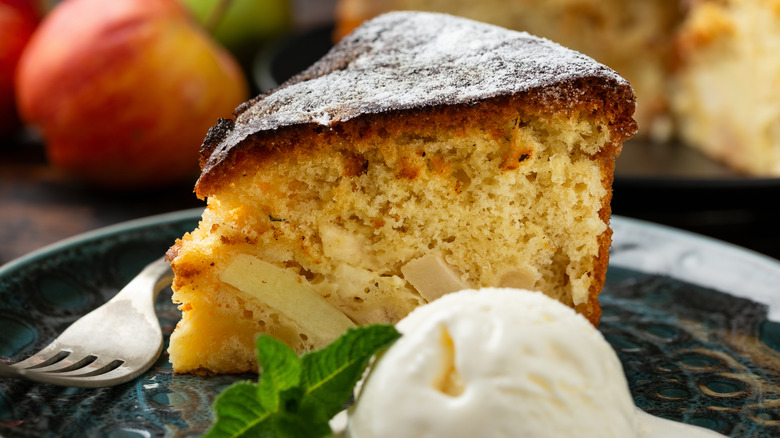 A slice of apple cake next to a scoop of vanilla ice cream on a plate