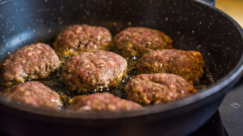 Small burgers being fried in oil
