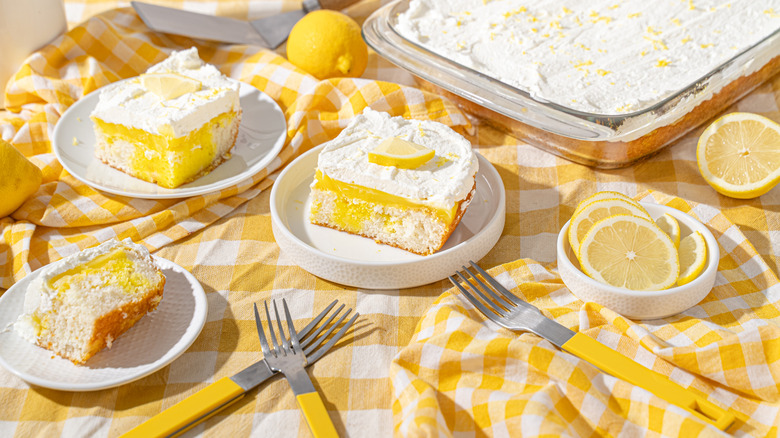 Lemon cake with frosting on plates with a yellow checkered tablecloth underneath