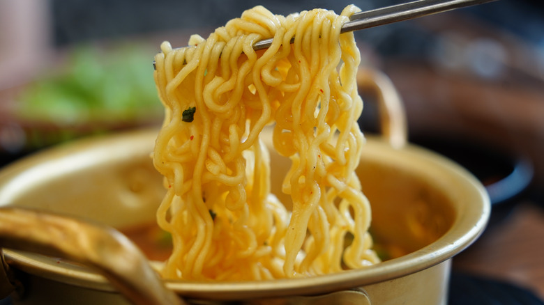 Close-up of instant ramen noodles lifted with chopsticks