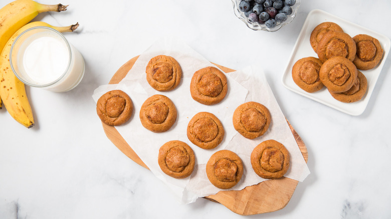 Thumbprint peanut butter cookies on a counter with bananas and blueberries.