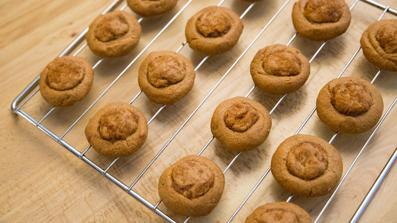 Thumb print peanut butter cookies on a rack.