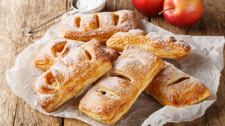 A pile of puff pastry apple turnovers with powdered sugar
