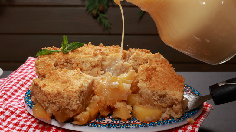 Custard pouring onto plate of apple dump cake