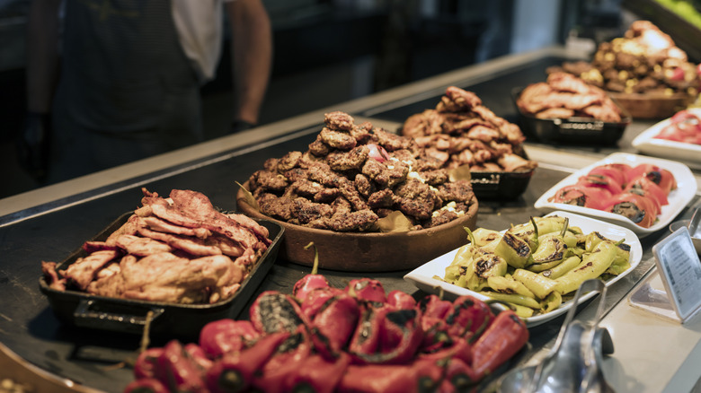 A buffet of multiple dishes of meat and grilled vegetables
