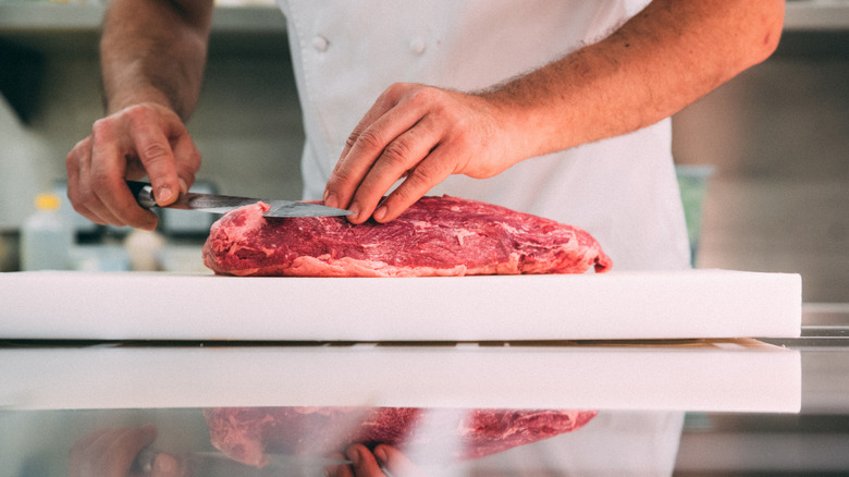 Steak being cut at a meat counter