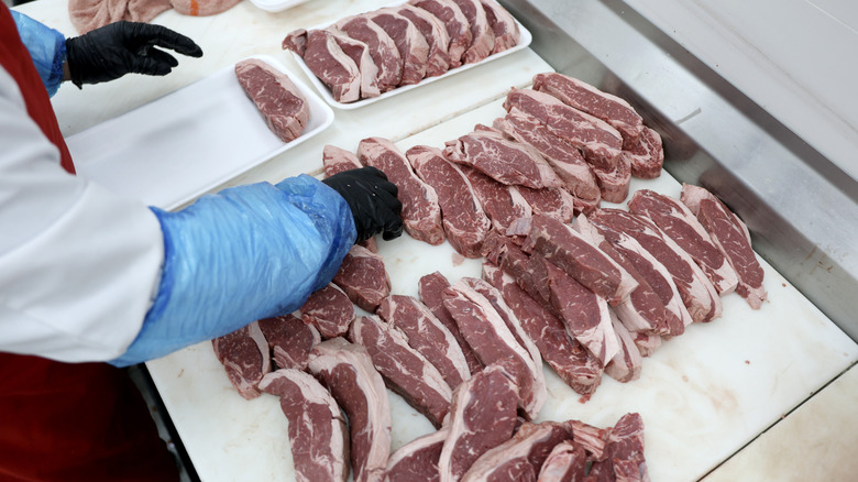 Overhead view of meat department employee packing meat while wearing gloves