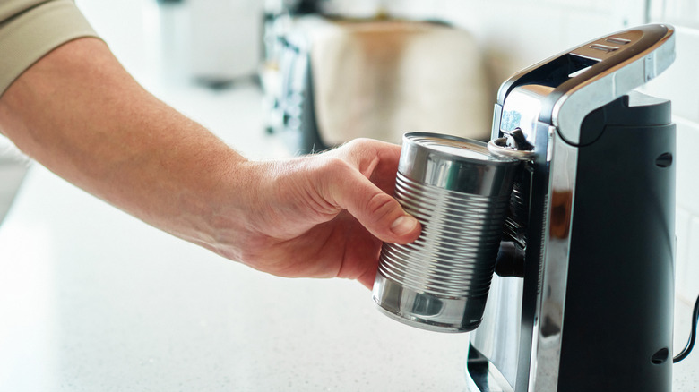 An electric can opener being used to open an unlabeled can