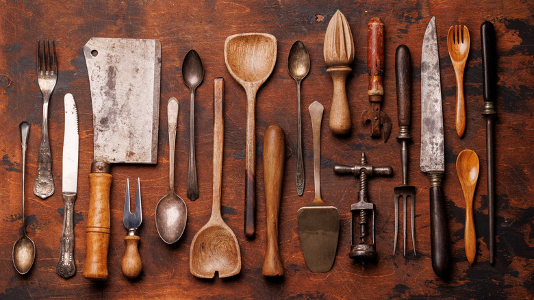 A wide variety of vintage kitchen utensils including can openers, knives, corkscrews, spoons, and more