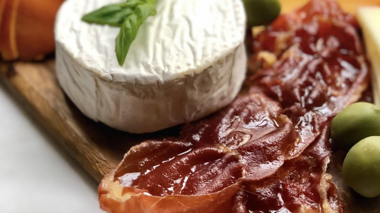 sliced candied prosciutto on board with brie