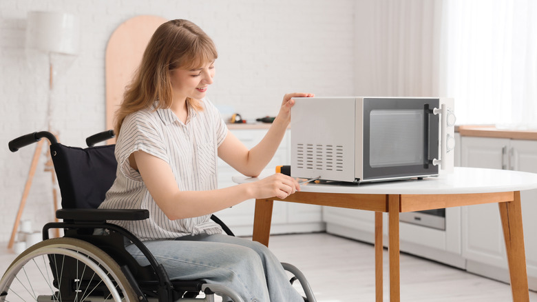 Woman unscrewing the side panel of a white microwave