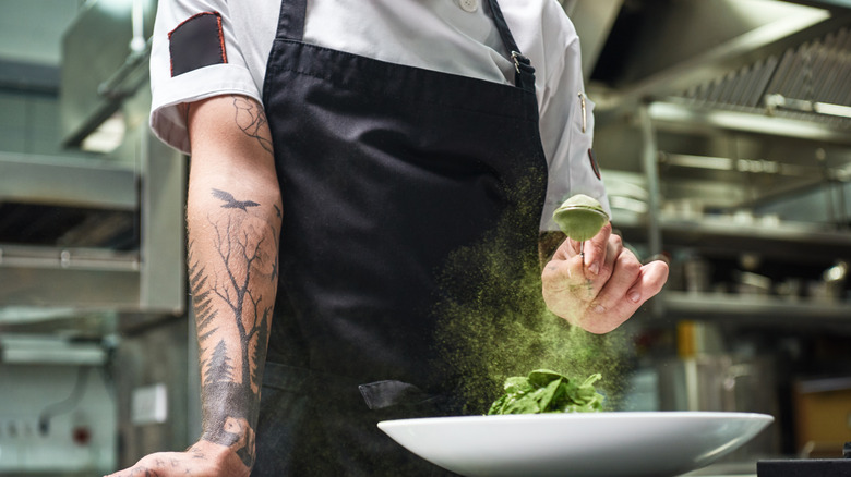 Chef with black apron preparing dish