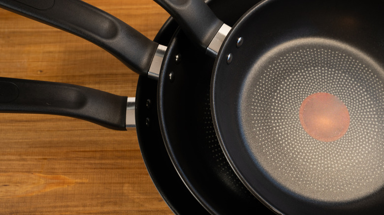 Nonstick frying pans stacked on a wooden counter