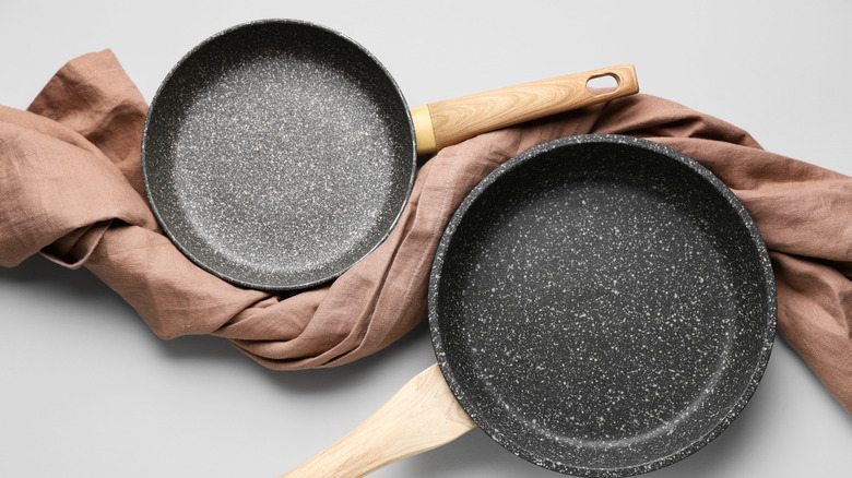 Pans with plastic handles on tea towel against a white background