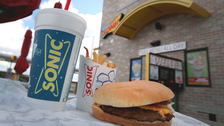 A Sonic burger, fries, and a drink in front of the drive-thru window