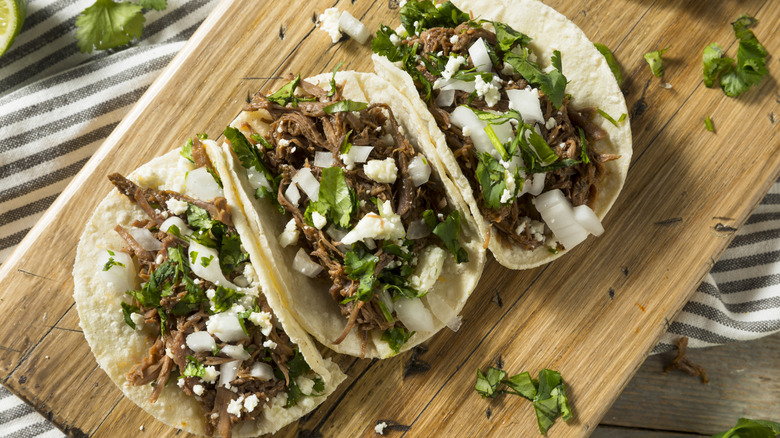 three tacos on a wooden board