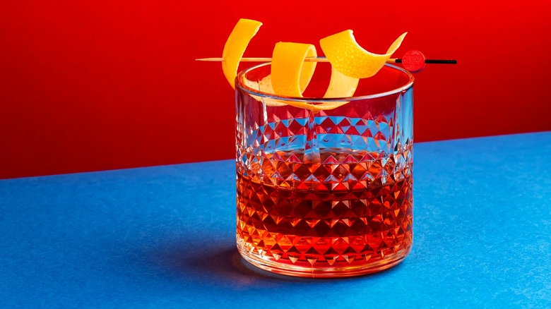 A Sazerac cocktail with a blue and red background