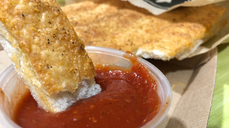 Dipping breadsticks in marinara sauce