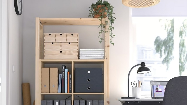 An IVAR shelving unit in a home office neatly stores folders, storage boxes, and books, with a potted plant placed on top