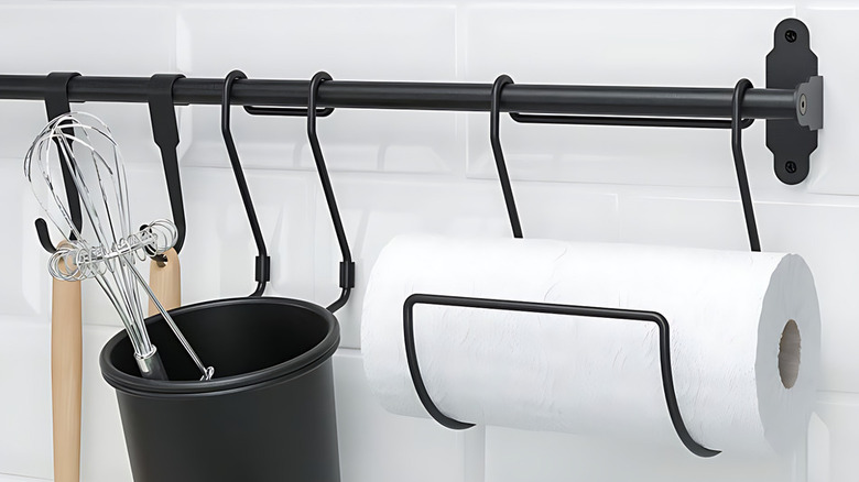 IKEA Fintorp rail system with hanging utensils, a container for whisks, and a paper towel holder mounted on a white tiled wall.