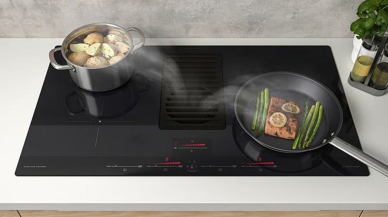 Food cooking on the Förnebo induction cooktop with smoke effects added to show how the downdraft works