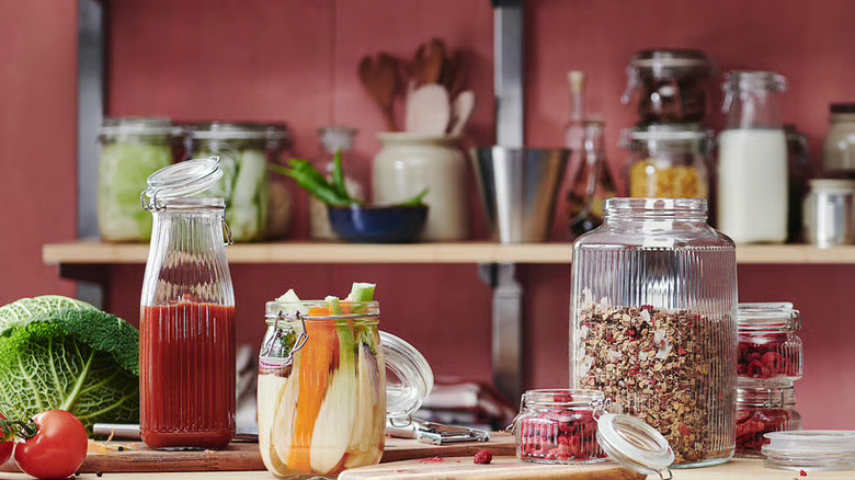 Glass jars filled with juice, vegetables, etc. in front of pantry rack