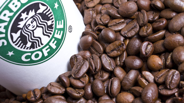 Starbucks coffee cup sitting in roasted coffee beans