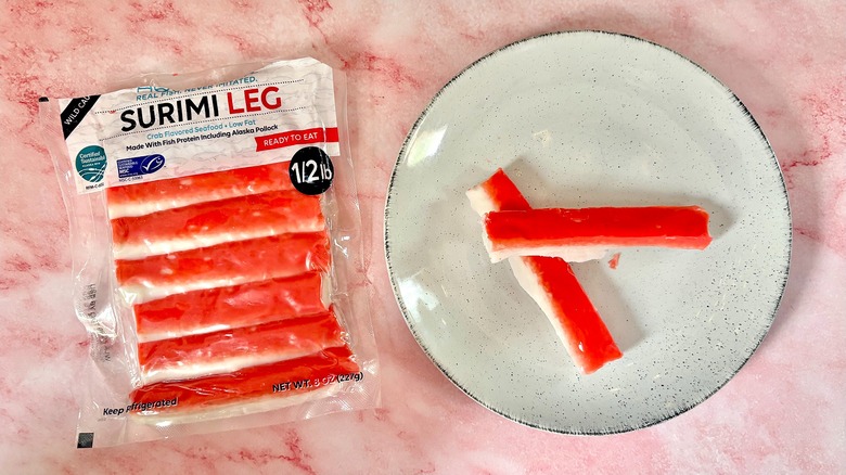 Package of Aquamar imitation crab next to imitation crab on white plate