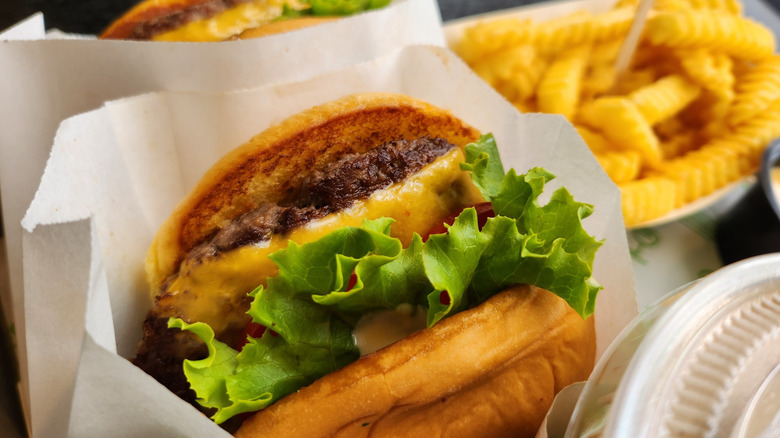Shake Shack hamburger in wrapper next to basket of fries