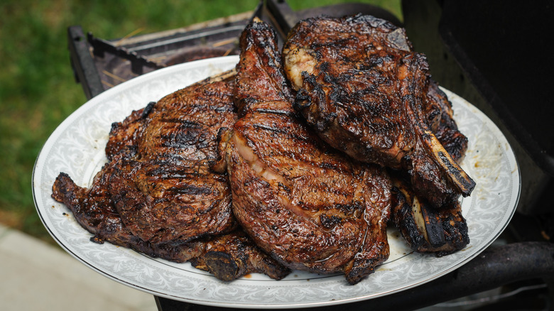 Several steaks plated just off the grill
