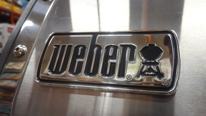 The Weber logo on a the lid of a polished steel grill
